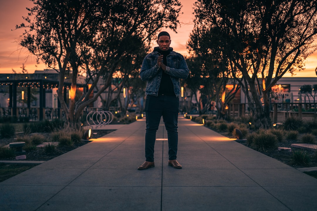 man in black jacket standing on gray concrete pavement during daytime