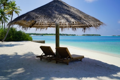 brown wooden lounge chairs on beach shore during daytime