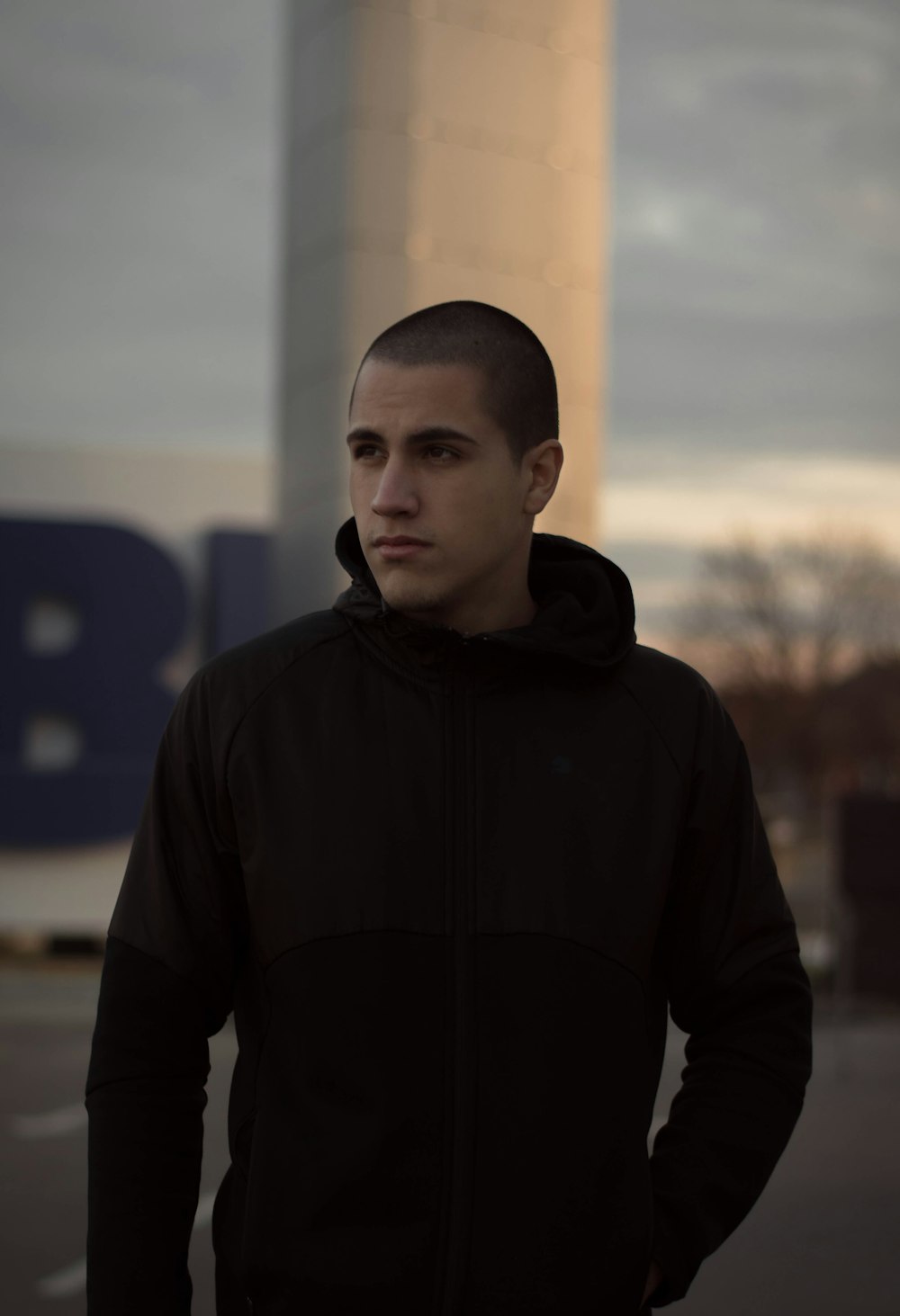 man in black hoodie standing near building during daytime