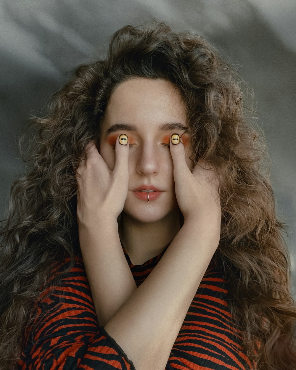 woman in red and black stripe long sleeve shirt covering her face with her hand