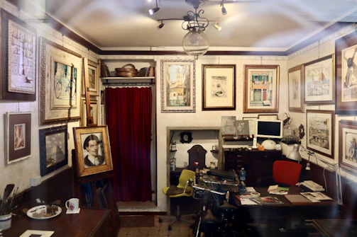 A cozy studio corner with several unique oil paintings displayed on the wall.