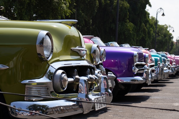 A row of colorful cars lined up under bright sunlight ready for sale