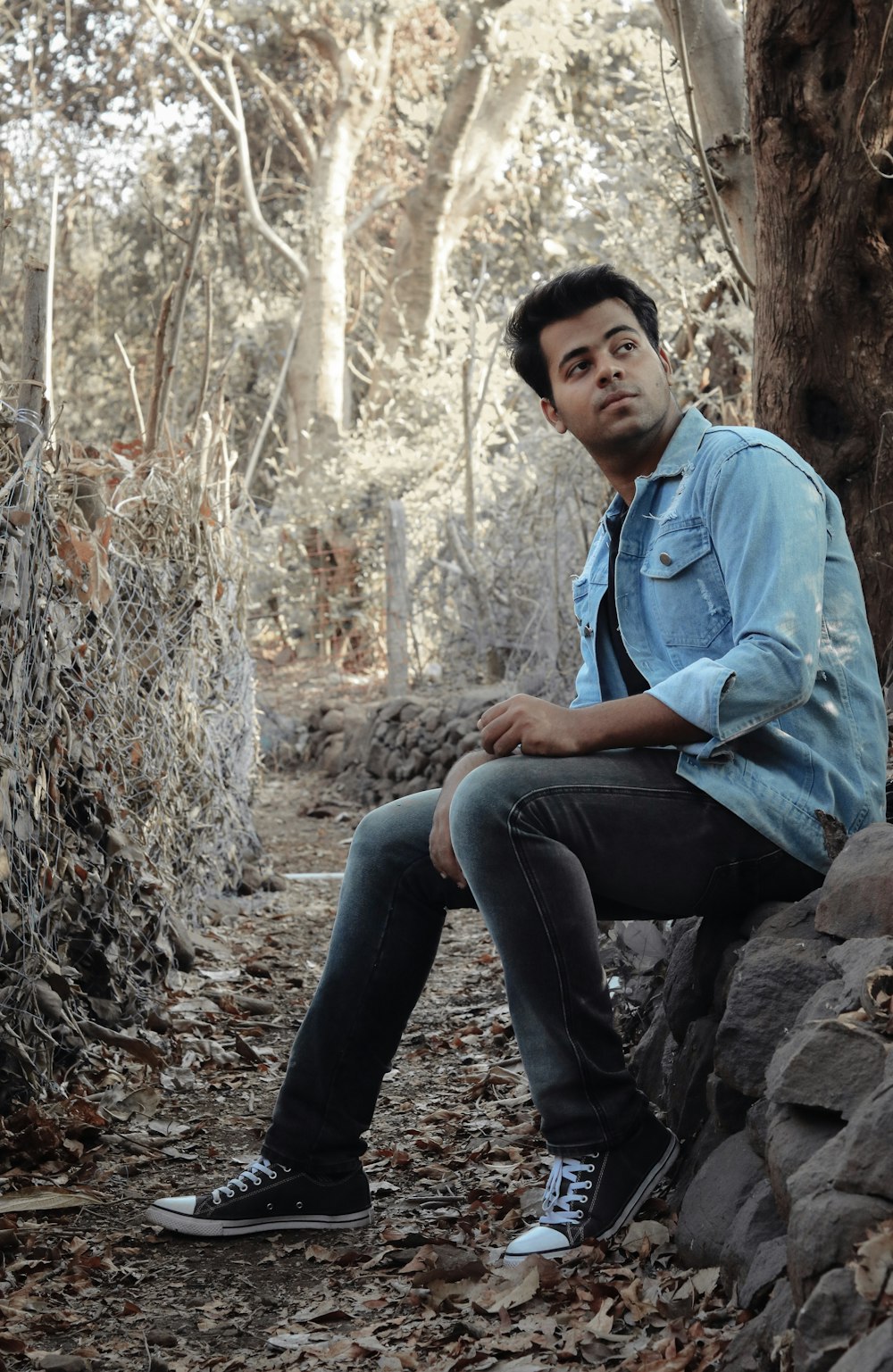 man in blue dress shirt and black pants sitting on rock