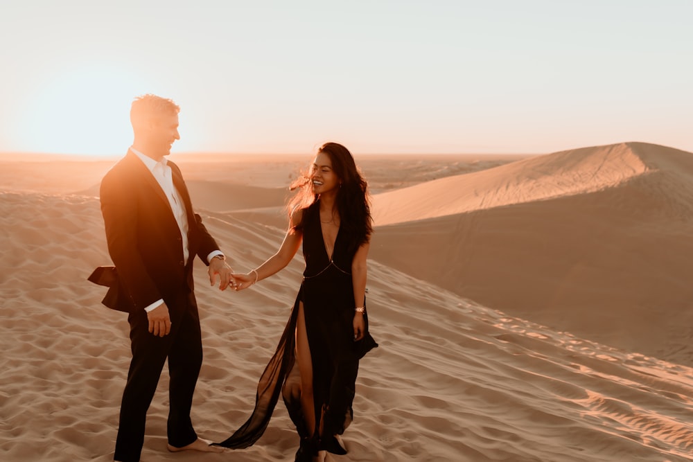 man and woman holding hands while walking on beach during daytime