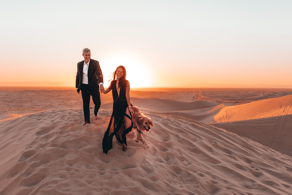 2 women and man standing on brown sand during daytime