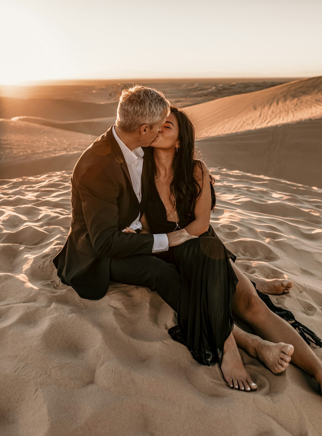 man in black suit sitting on sand