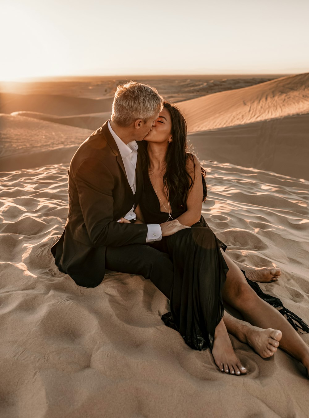 man in black suit sitting on sand