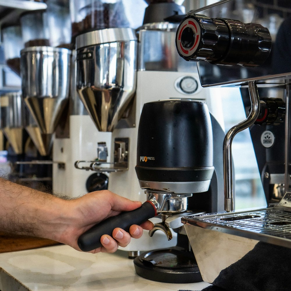 Persona sosteniendo una cafetera plateada y negra