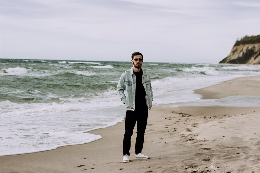 woman in gray jacket standing on beach during daytime