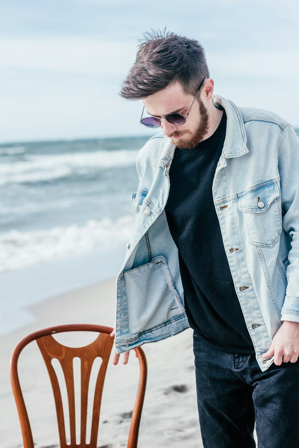 Hombre con chaqueta de mezclilla azul sosteniendo cubo de plástico rojo