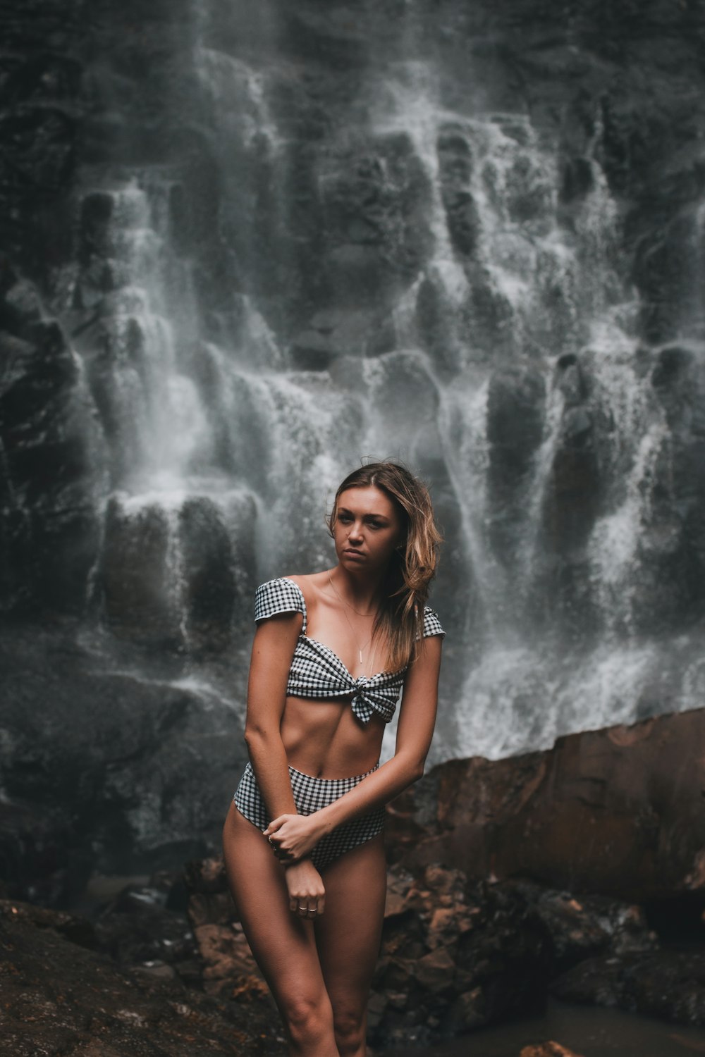 woman in black and white bikini standing on rock