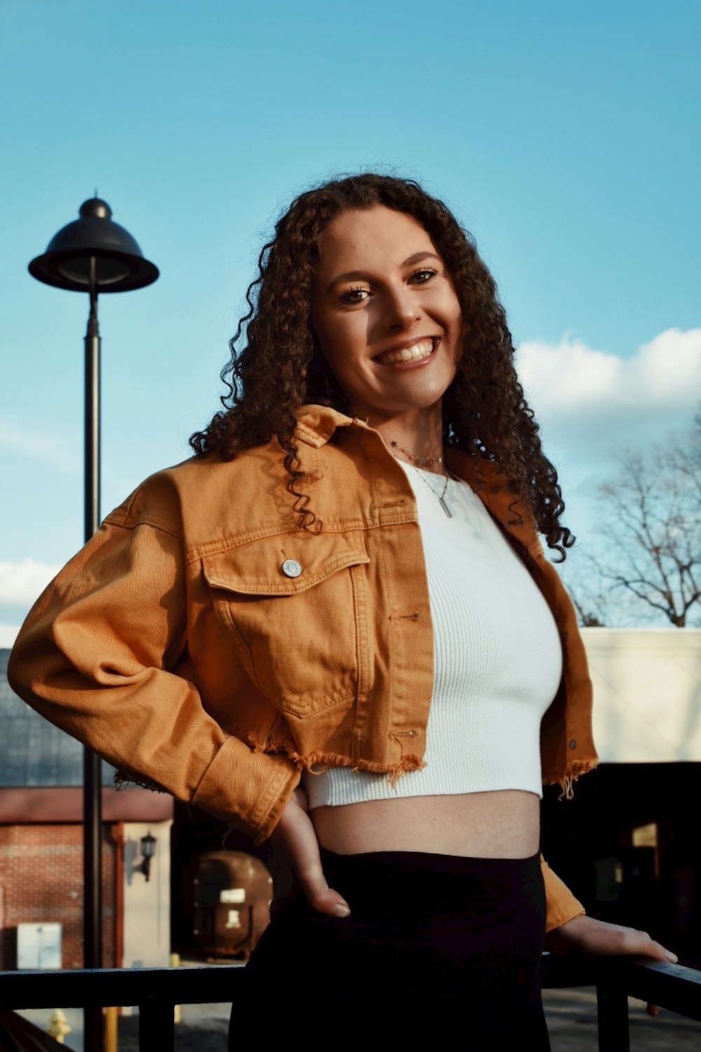 woman in brown button up jacket standing near black lamp post