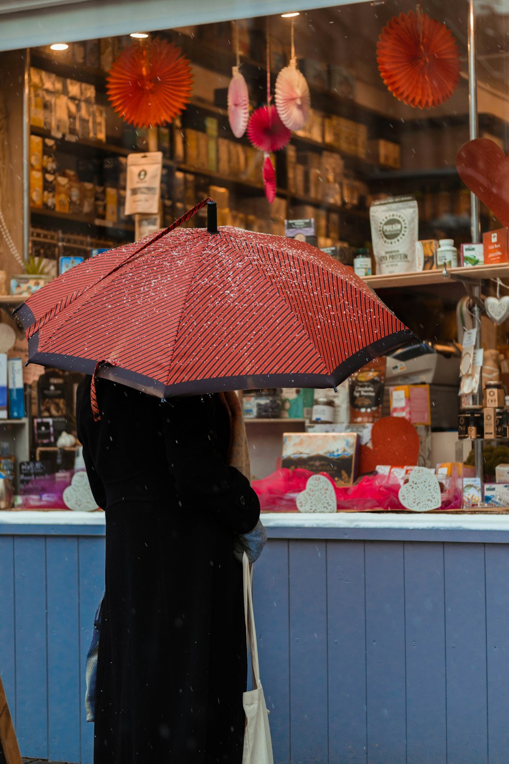 person in black coat holding red umbrella