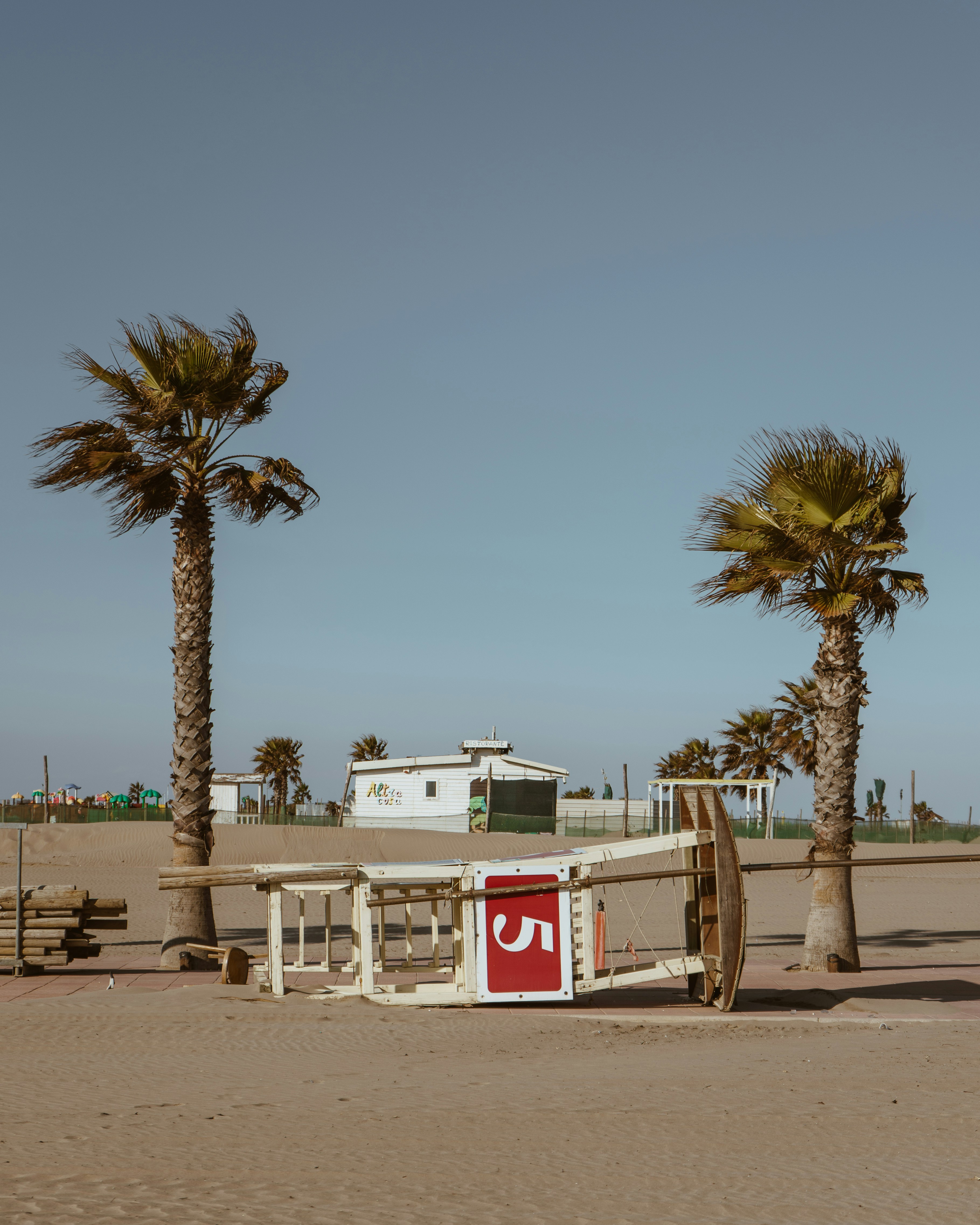 white and red concrete building near palm trees under blue sky during daytime
