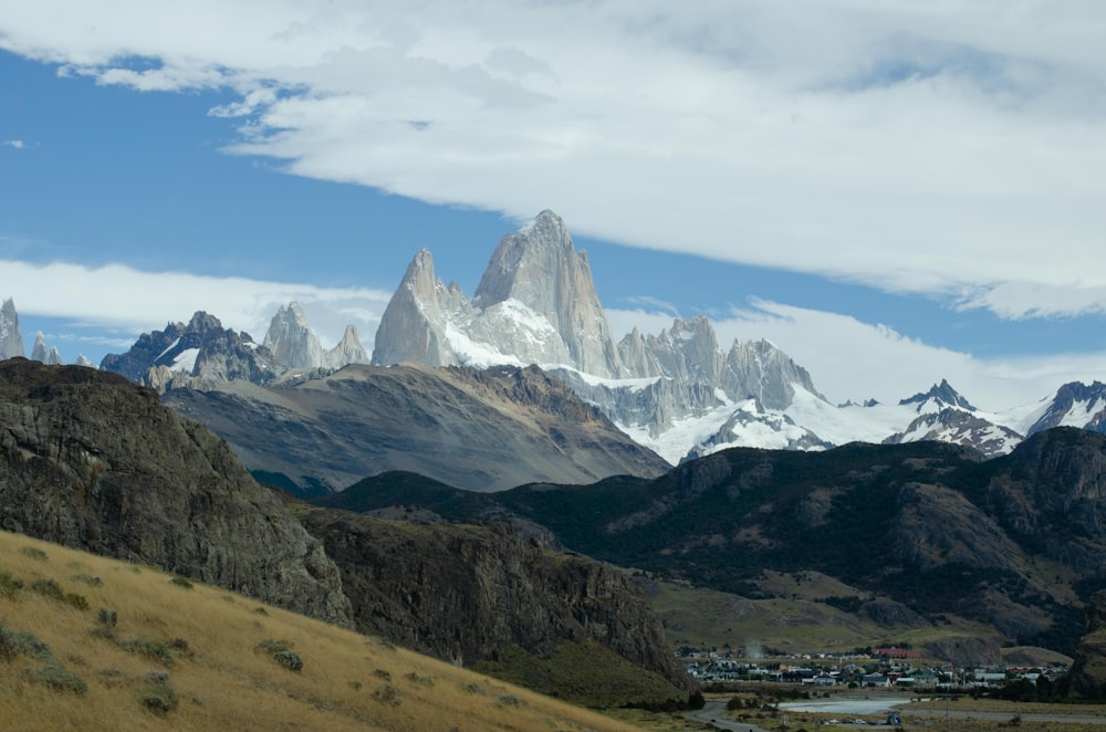 snow covered mountains under white clouds and blue sky during daytime