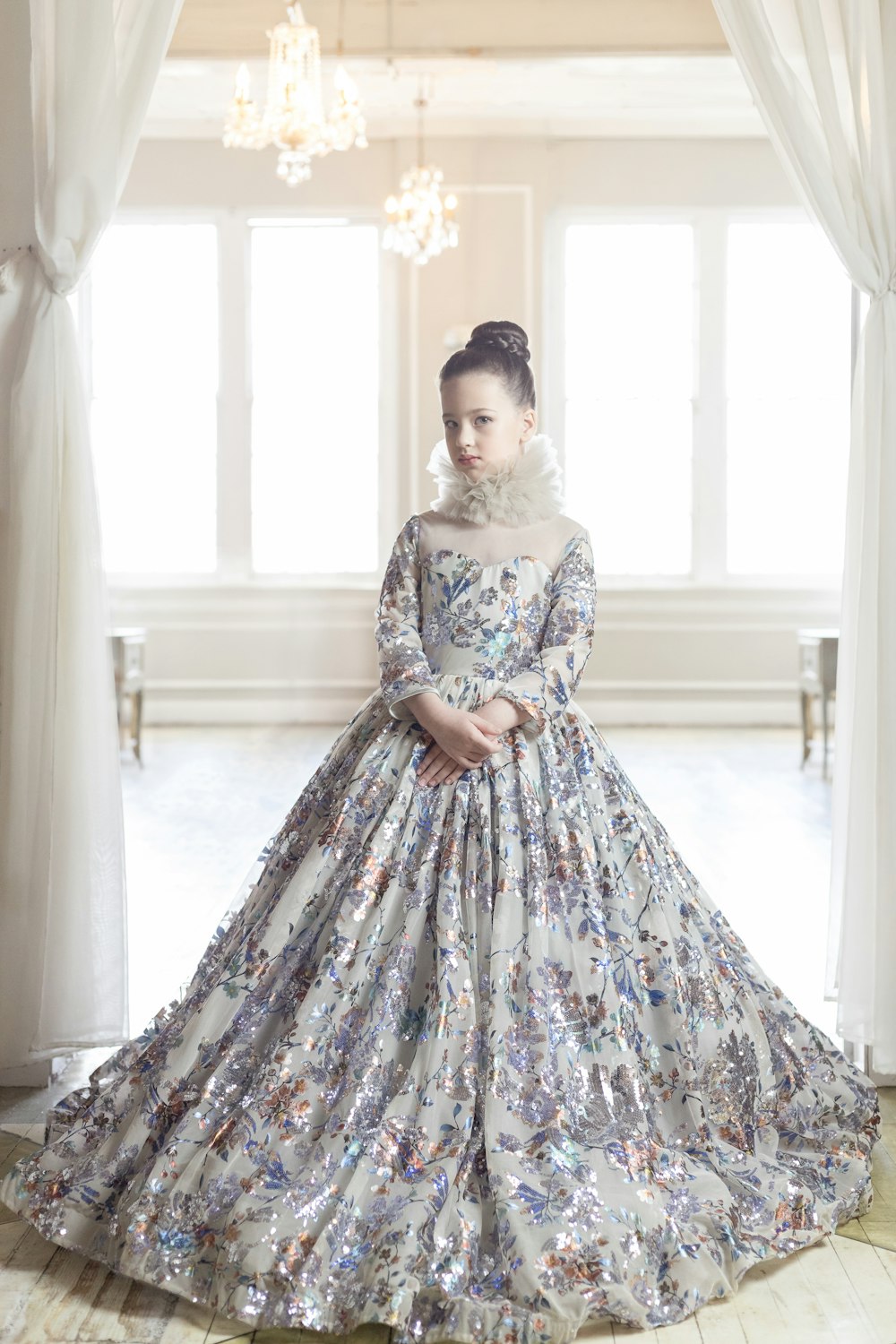 woman in white and blue floral dress standing near window