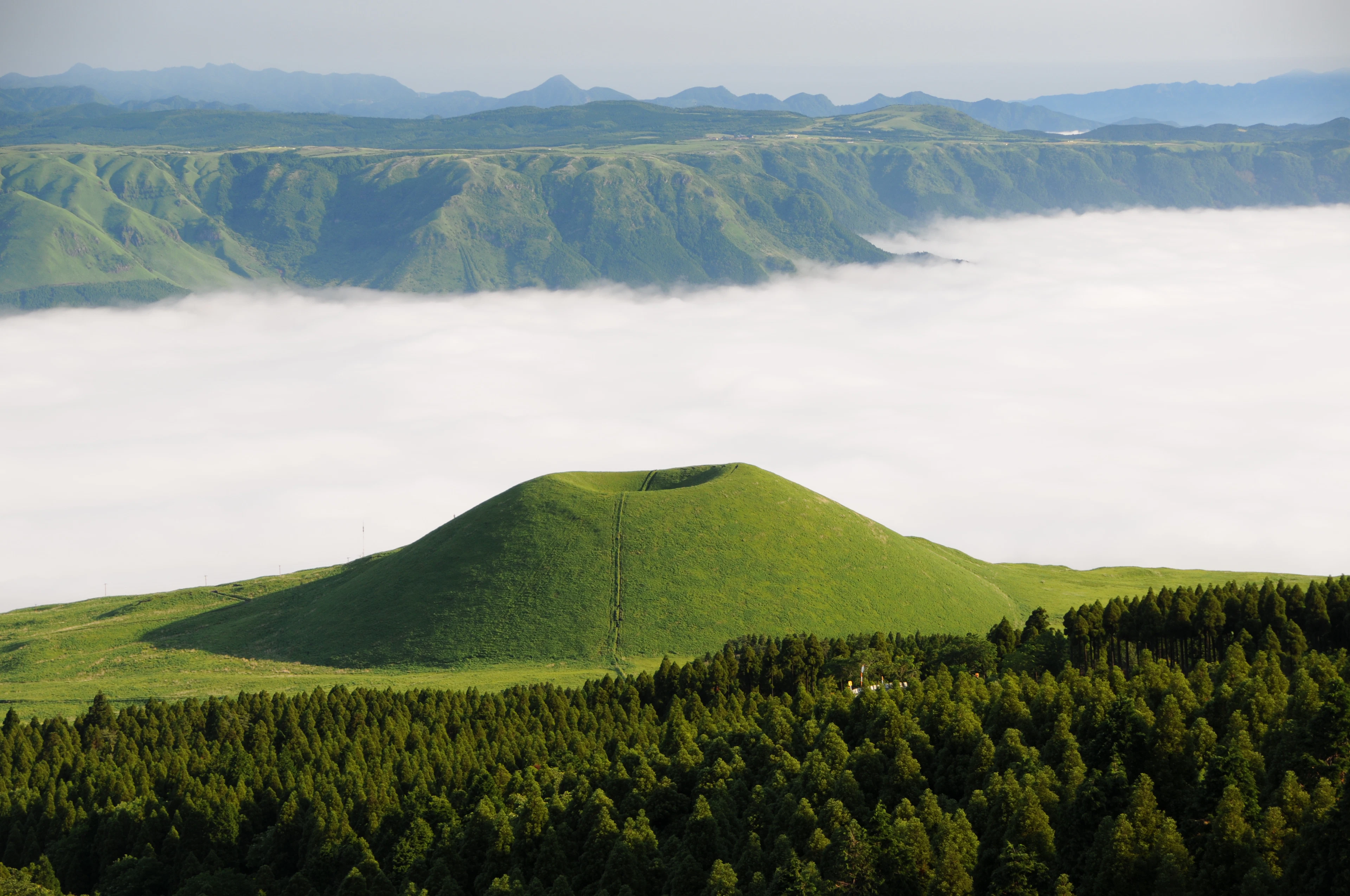 A green volcanic cone above a sea of cloud in the Aso caldera