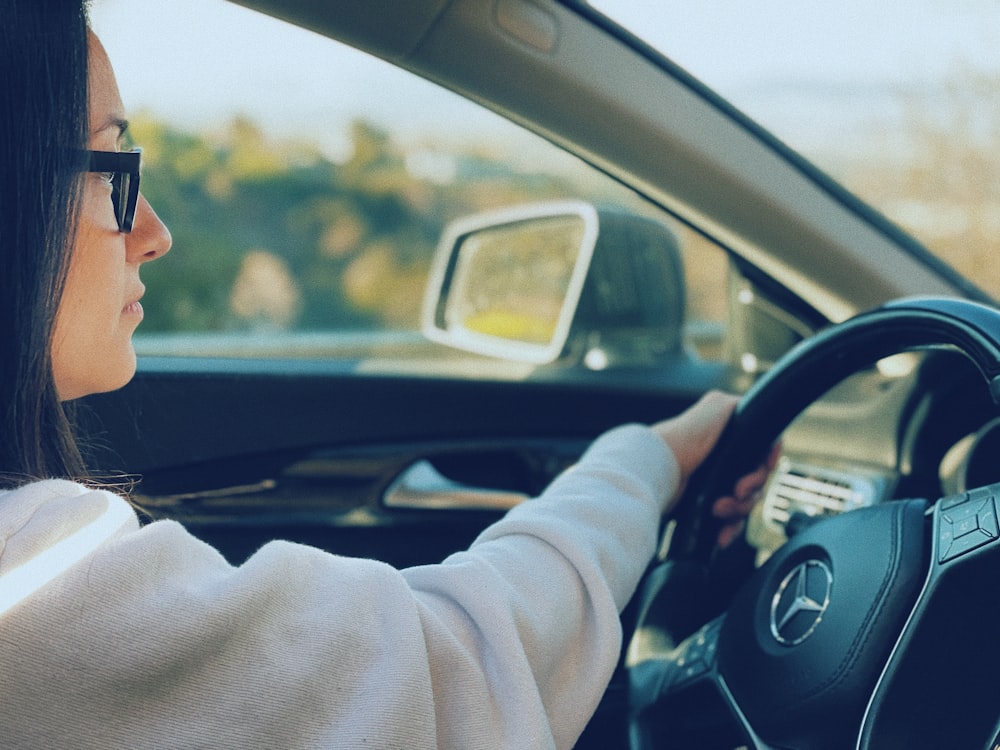 man in white sweater driving car during daytime