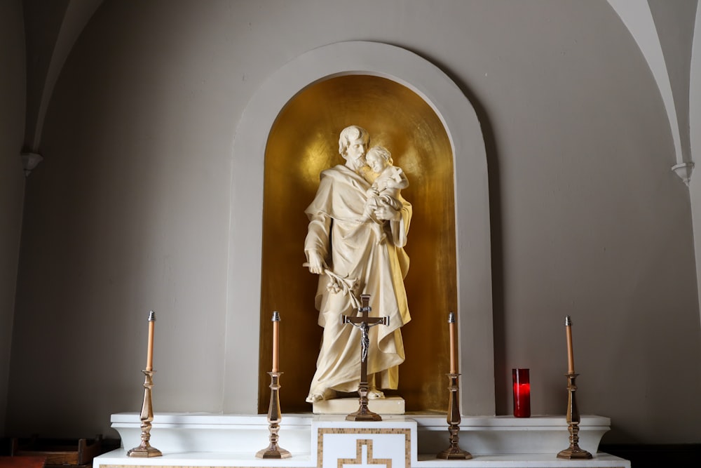 gold statue of man holding cross