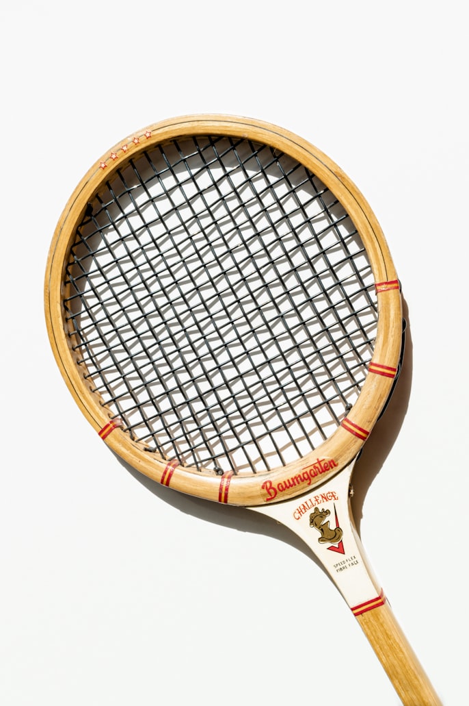 A classic wooden tennis racket displayed on a white background, showing the vintage string pattern and craftsmanship