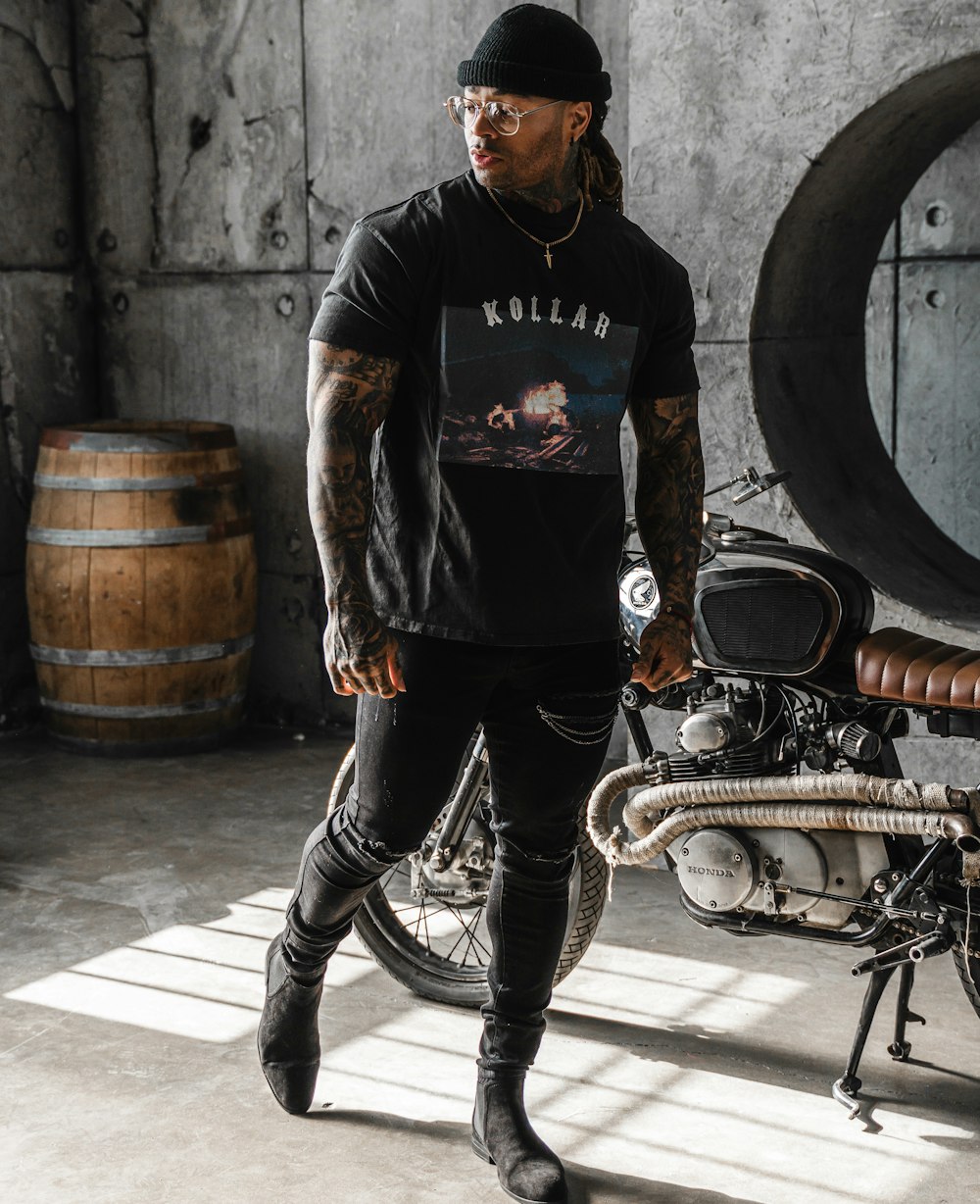 man in black long sleeve shirt and black pants standing beside bicycle