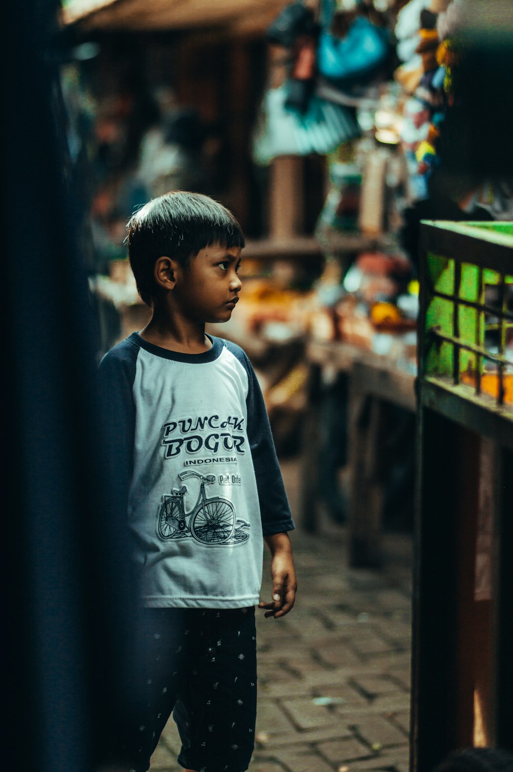 boy in white and black crew neck t-shirt standing on street during daytime