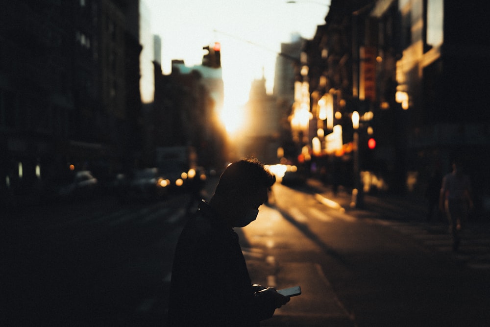 man in black jacket standing on sidewalk during daytime