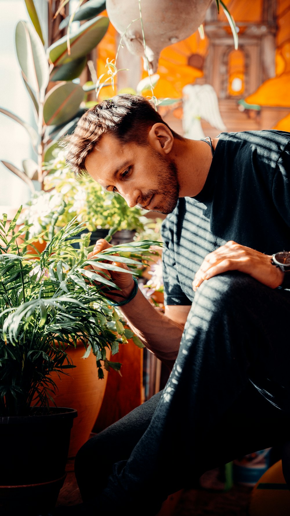 man in black crew neck t-shirt holding green plant