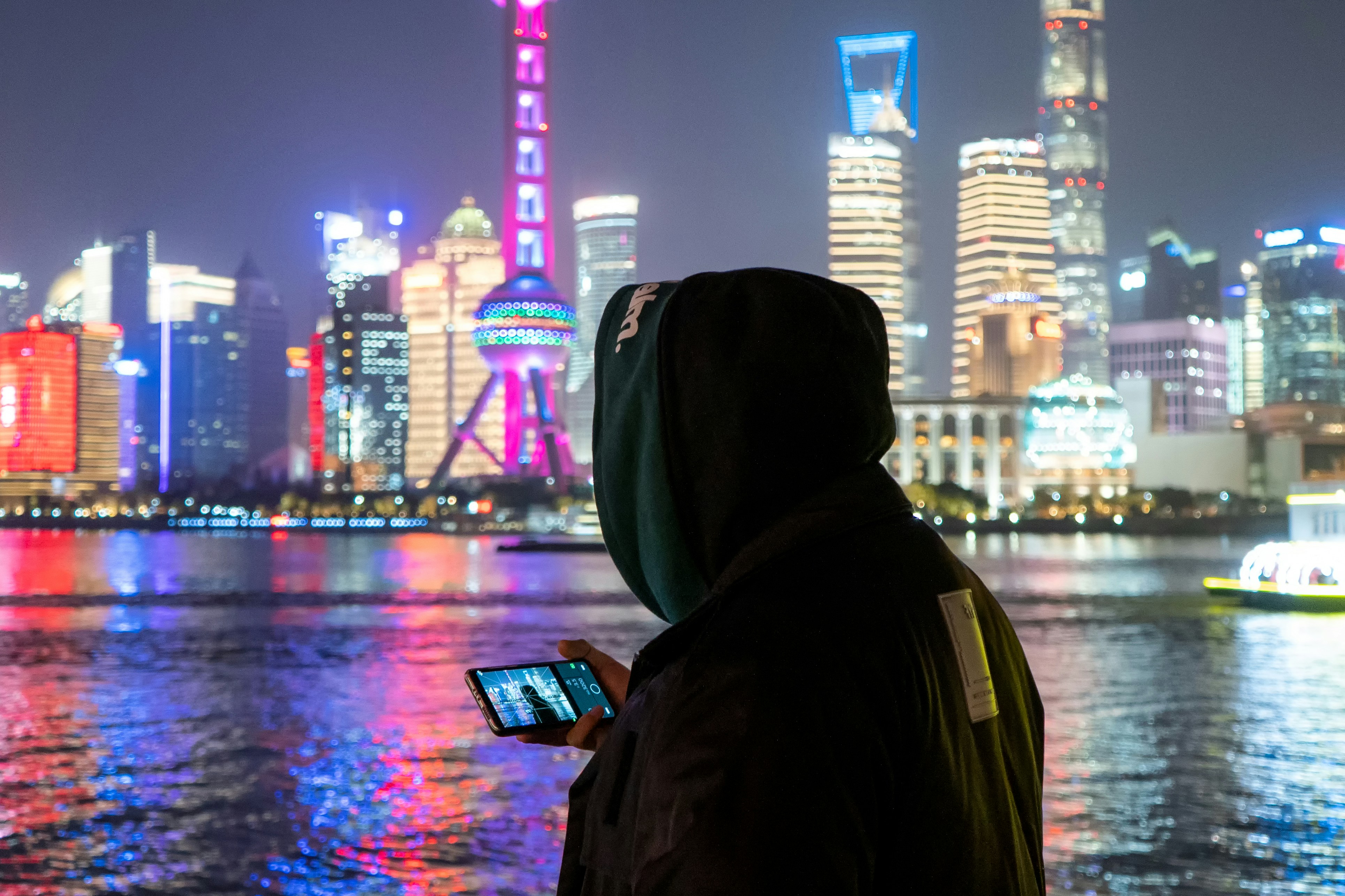 person in black hoodie standing near body of water during night time