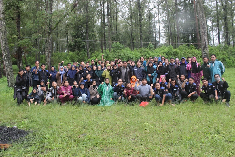 A vibrant group photo of a corporate team enjoying a company gathering in a lush outdoor setting.