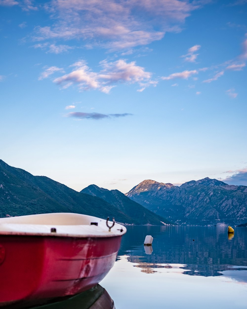 barca bianca sul lago vicino alle montagne sotto il cielo blu durante il giorno