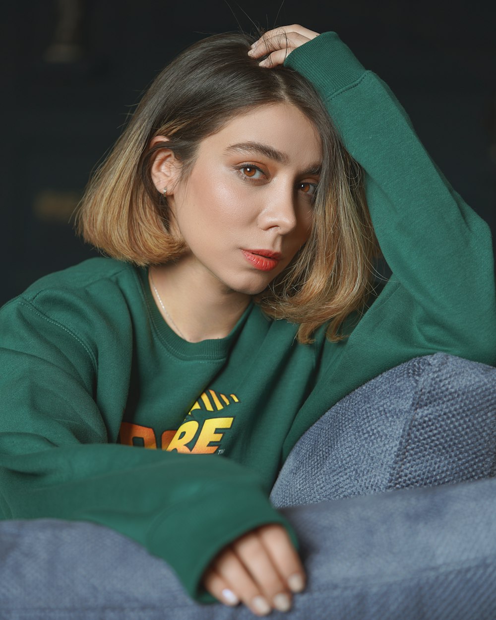 woman in green long sleeve shirt lying on gray textile