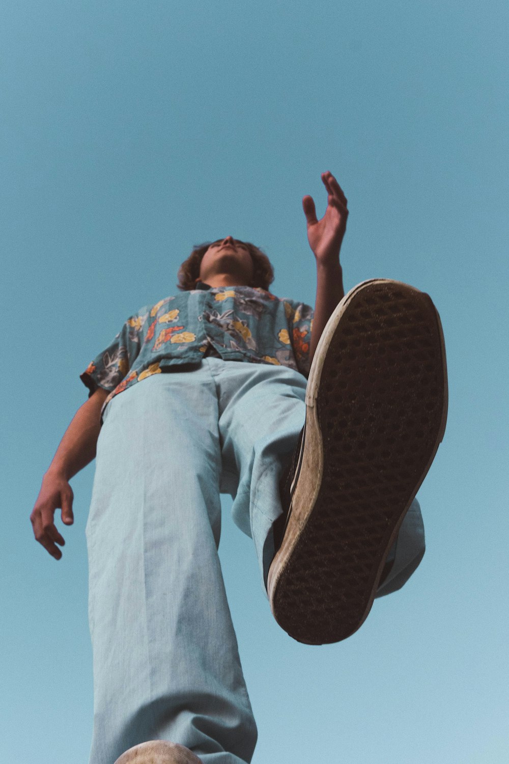 man in blue white and red floral button up shirt and gray pants sitting on brown