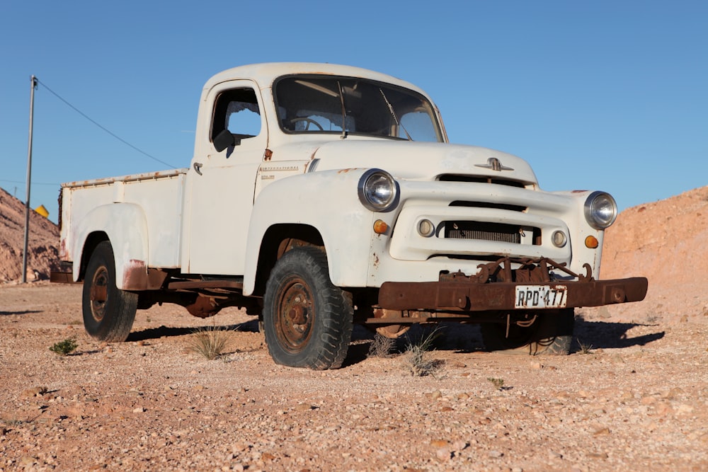white single cab pickup truck on brown dirt ground during daytime
