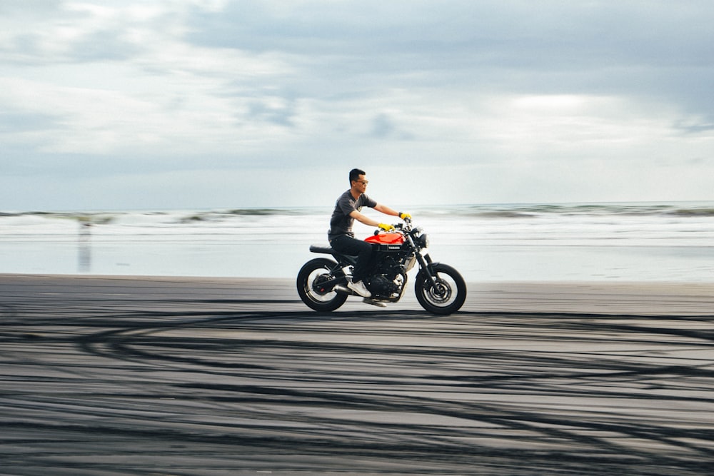 Un hombre está montando una motocicleta en la playa