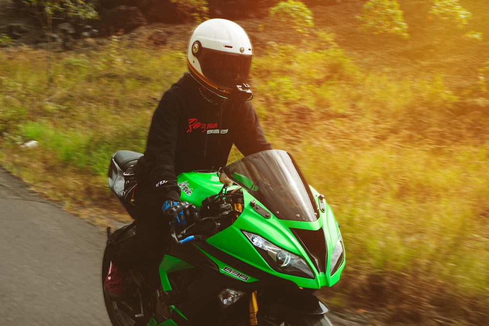 a person riding a green motorcycle on a road