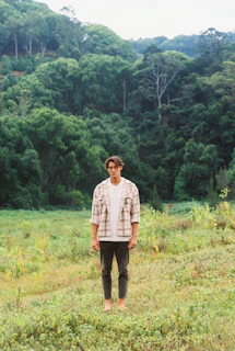 A person wearing a Sylva t-shirt standing barefoot on grass, embodying calm and connection with nature.