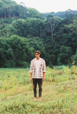 A person wearing a Sylva t-shirt standing barefoot on grass, embodying calm and connection with nature.