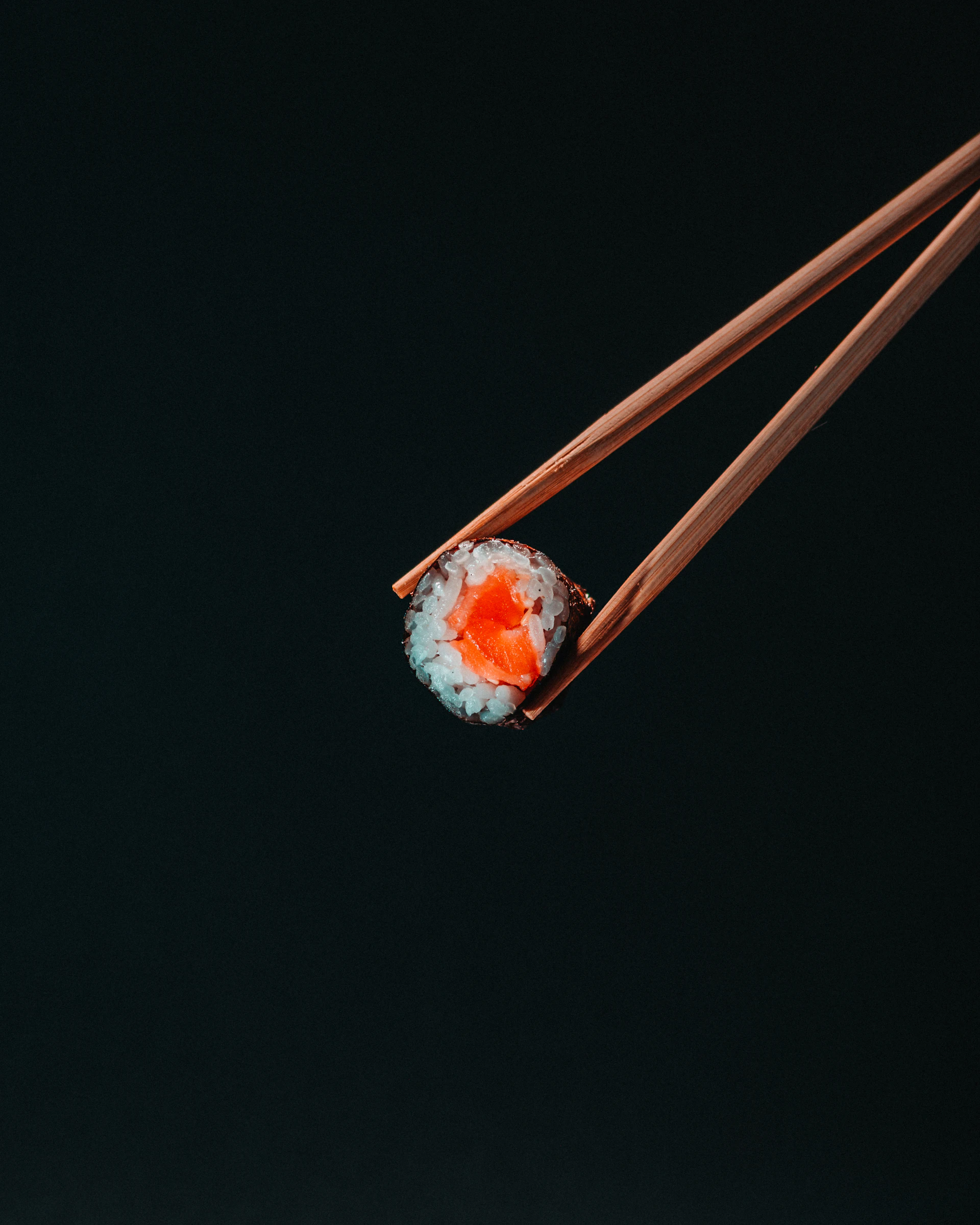 A single maki piece lifted with chopsticks