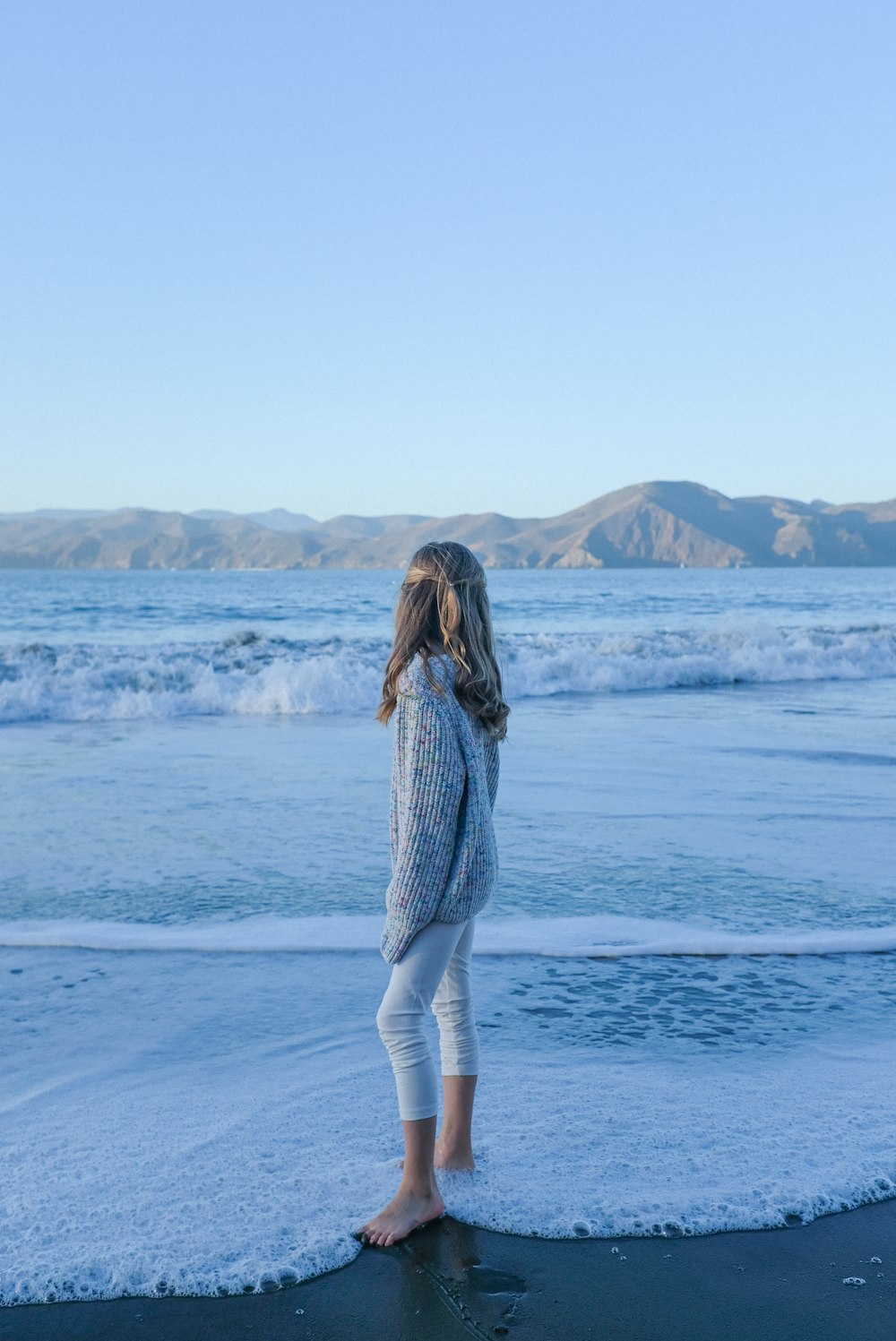 woman in white and black stripe dress standing on white sand during daytime