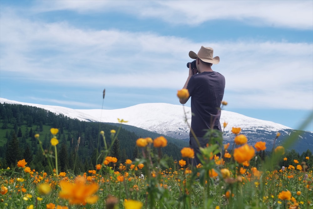 person in black jacket and brown hat standing on yellow flower field during daytime