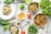 A vibrant display of fresh vegetables and herbs on a wooden kitchen table.