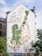 A large mural is painted on the side of a building, featuring a dominant green and beige color scheme. The artwork depicts a group of people engaged in various activities, including climbing a ladder and raising a fist, symbolizing resistance and community action. There's text in German integrated into the design, which emphasizes change and collaboration.