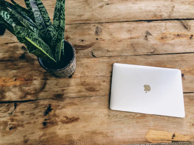 A stylish table AC placed on a wooden desk beside a laptop.