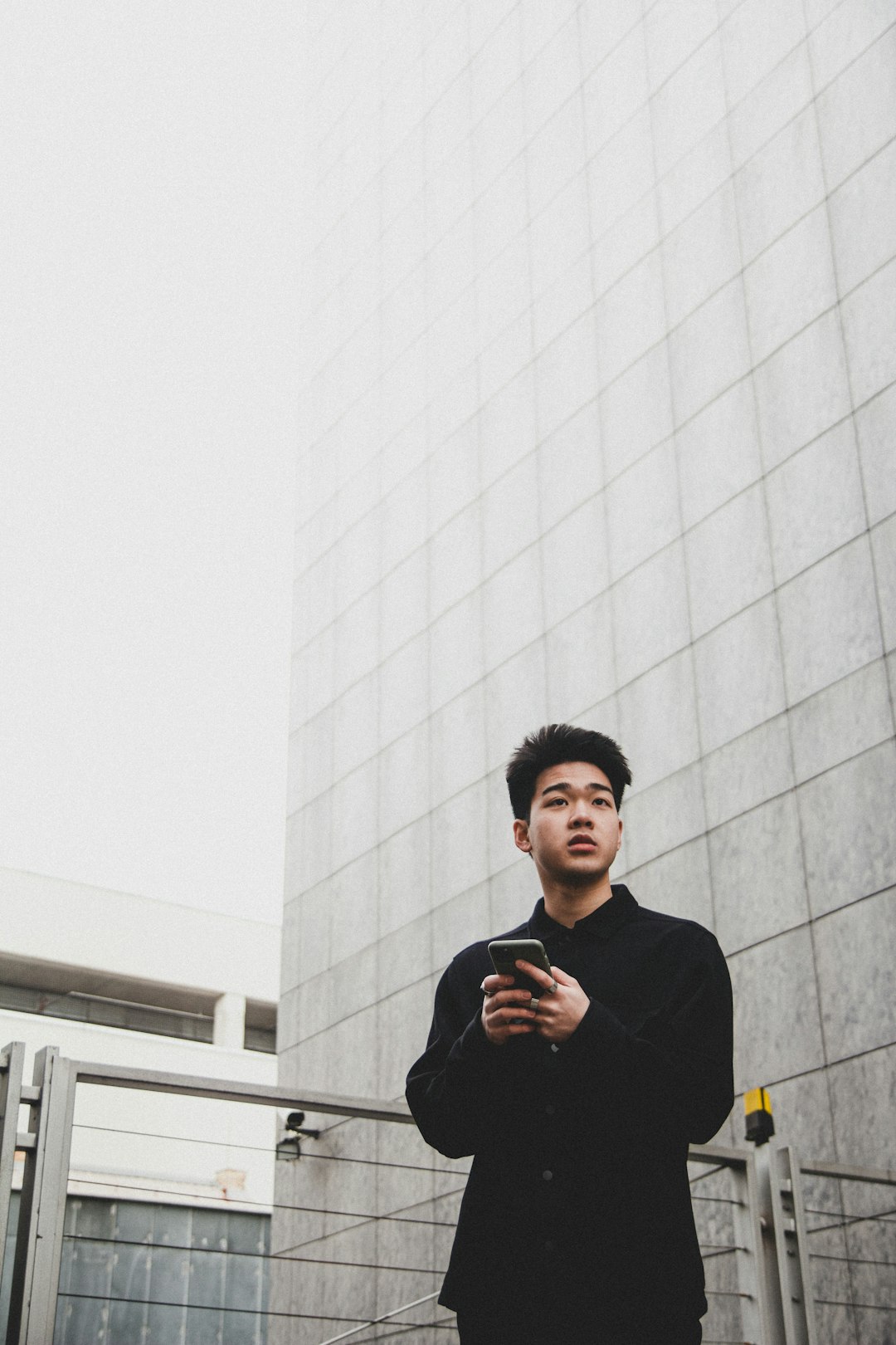 man in black sweater standing beside white wall