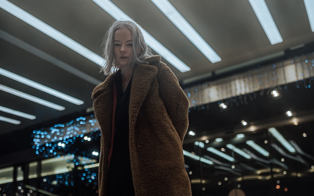 woman in brown coat standing inside building