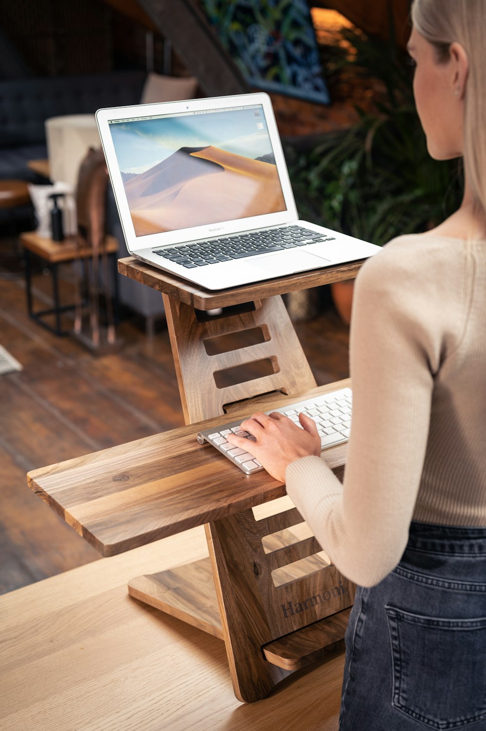 흰색 긴 소매 셔츠를 입은 여자는 MacBook Air를 사용하여 갈색 나무 의자에 앉아 있다