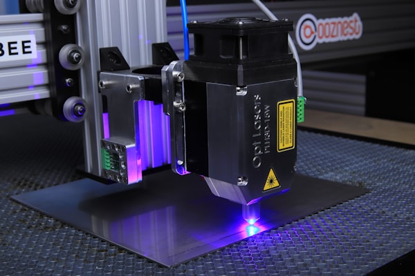 Close-up of laser head cutting through material with orange glow