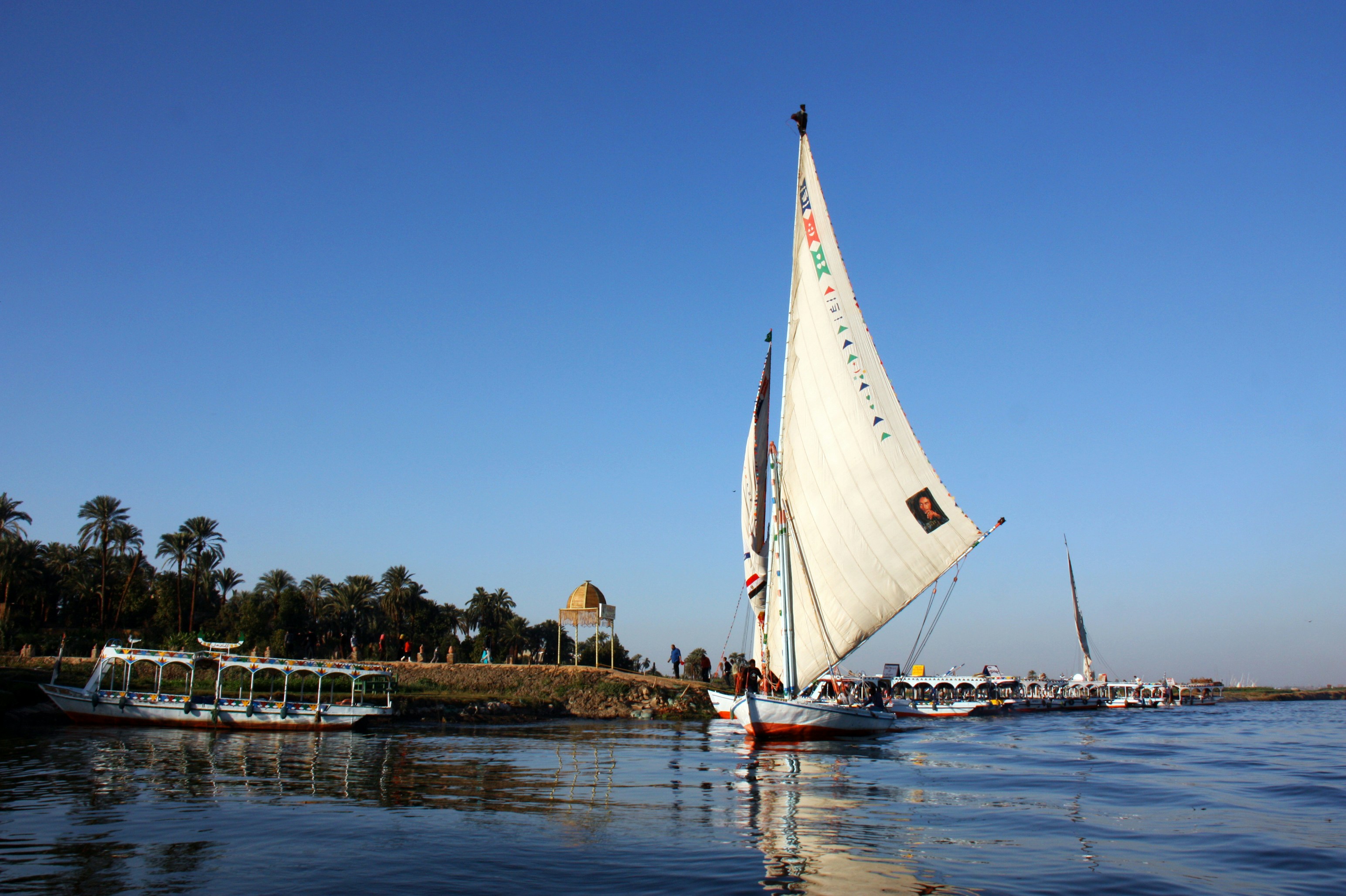 белая парусная лодка на воде рядом с коричневым деревянным причалом в дневное время