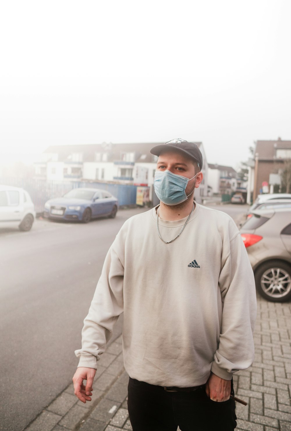 a man wearing a face mask standing on a sidewalk